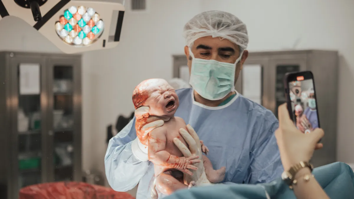 Sezaryenle doğan bebeği kucağında tutan Op. Dr. Hayri Aksüt