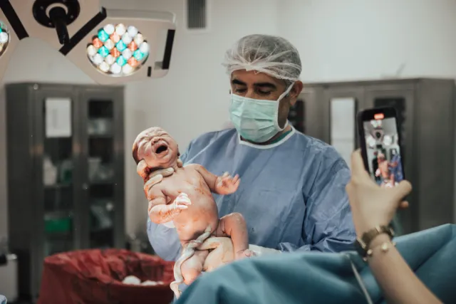 Ameliyathanede yenidoğanı kucağında tutan Op. Dr. Hayri Aksüt