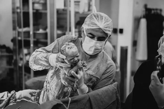Doğum sonrası yenidoğanı kucağına alan Op. Dr. Hayri Aksüt, siyah beyaz