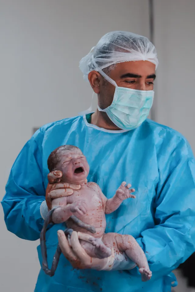 Op. Dr. Hayri Aksüt sezaryenle doğan bebeği kucağında tutuyor