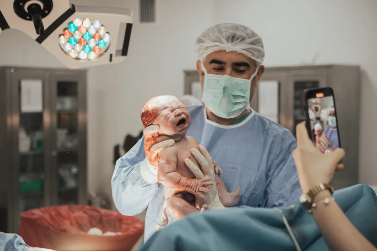 Doğum belirtilerinin ardından dünyaya gelen bebeği ameliyathanede aileye gösteren Op. Dr. Hayri Aksüt