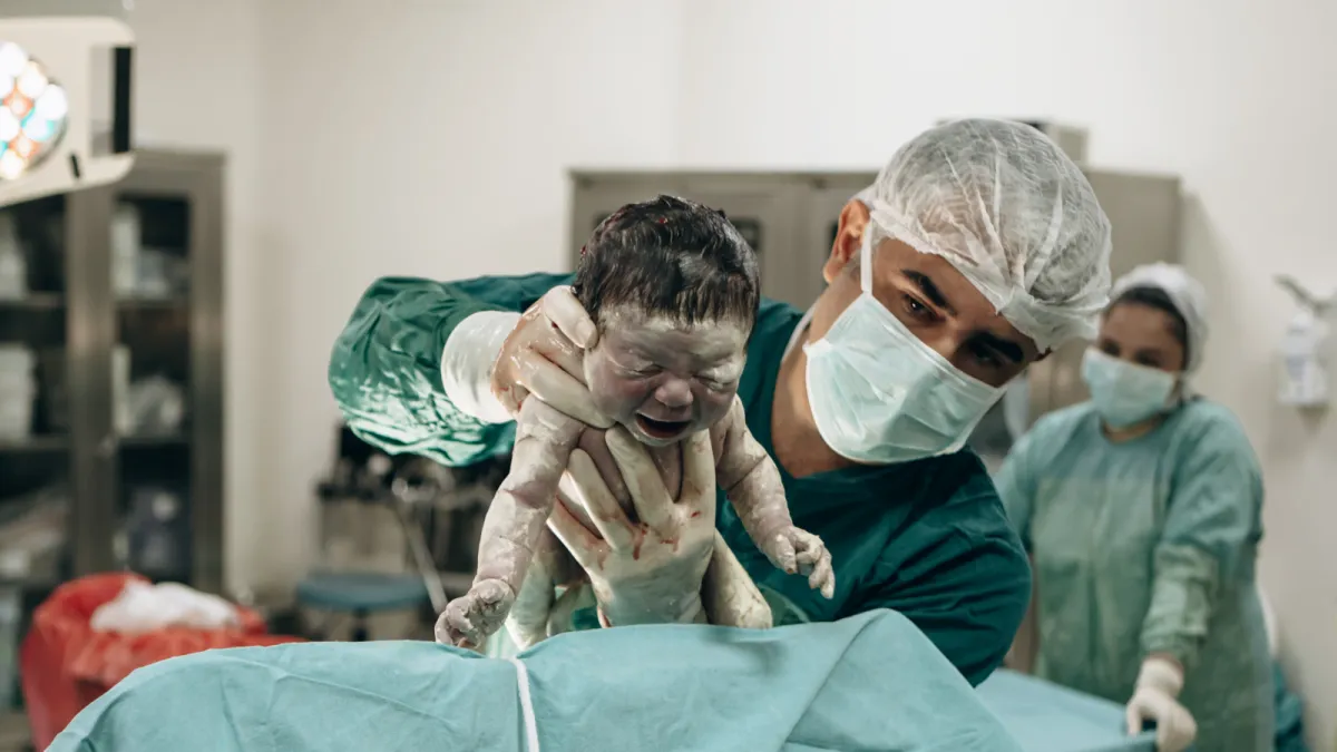 Ameliyathanede yenidoğanı ekibe gösteren Op. Dr. Hayri Aksüt